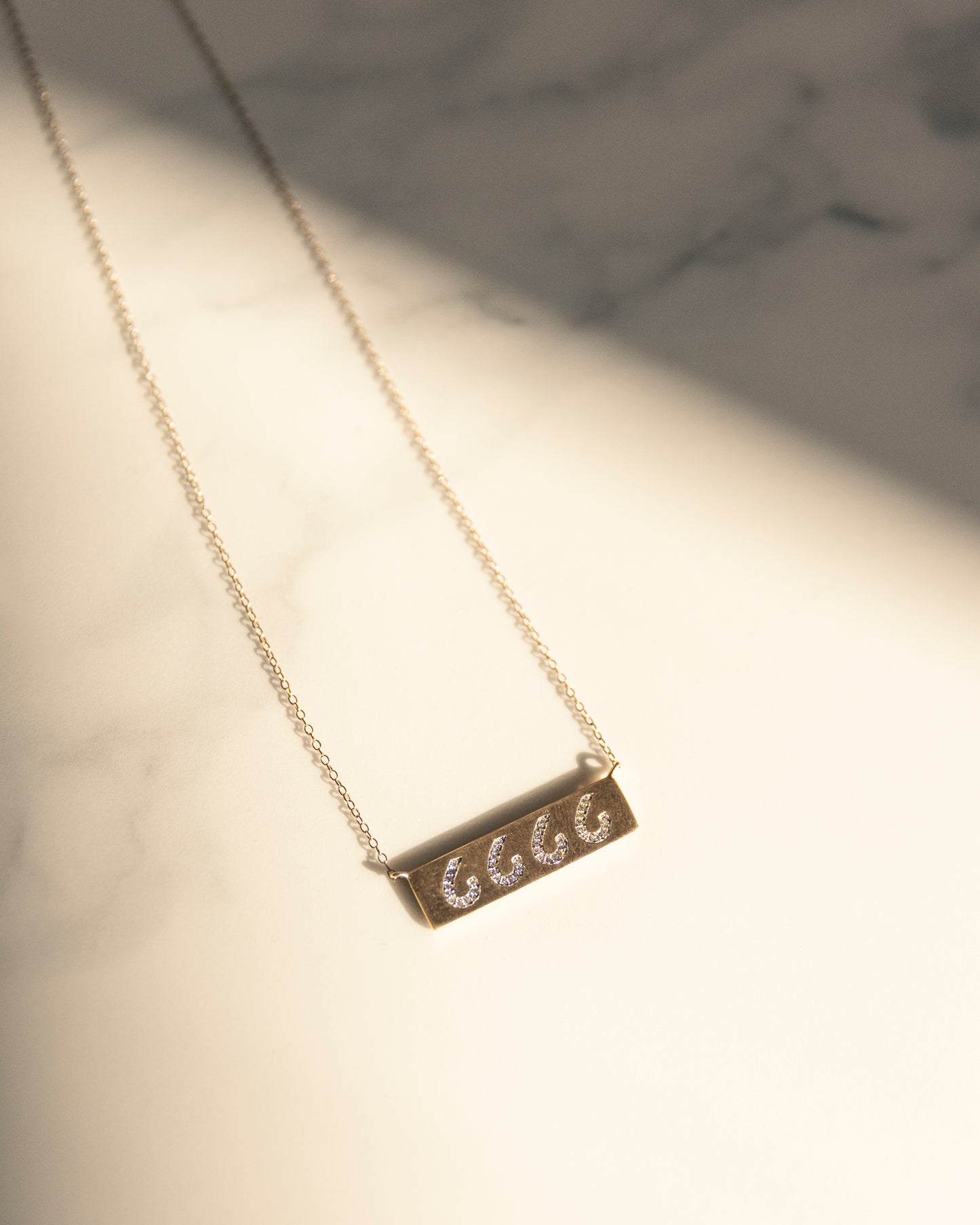 Lifestyle Image - A sleek diamond cattle brand bar necklace, featuring delicate diamond accents arranged in the shape of a personalized cattle brand symbol. A sophisticated tribute to Western heritage and individual style.
